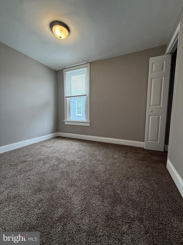 carpeted spare room featuring baseboards