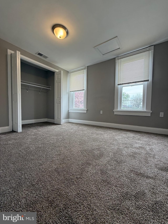 unfurnished bedroom featuring baseboards, visible vents, attic access, and a closet