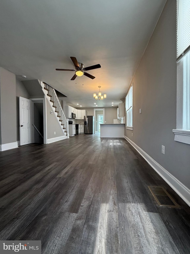 unfurnished living room with baseboards, visible vents, and dark wood-type flooring