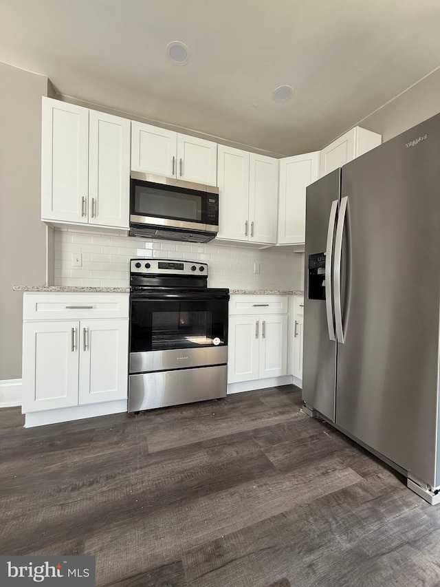 kitchen featuring decorative backsplash, stainless steel appliances, white cabinetry, and dark wood-type flooring