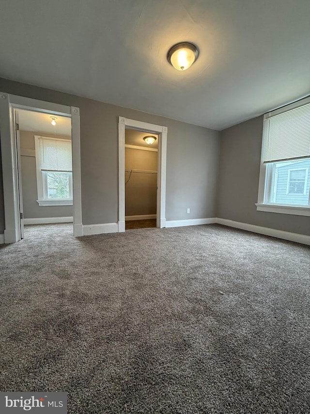 unfurnished bedroom featuring baseboards, carpet floors, and a walk in closet
