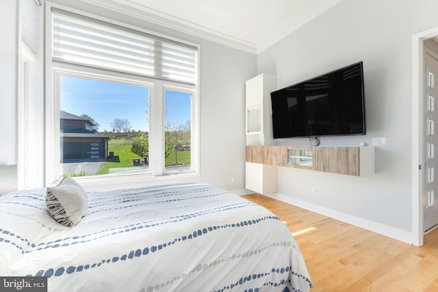 bedroom featuring baseboards, ornamental molding, and wood finished floors