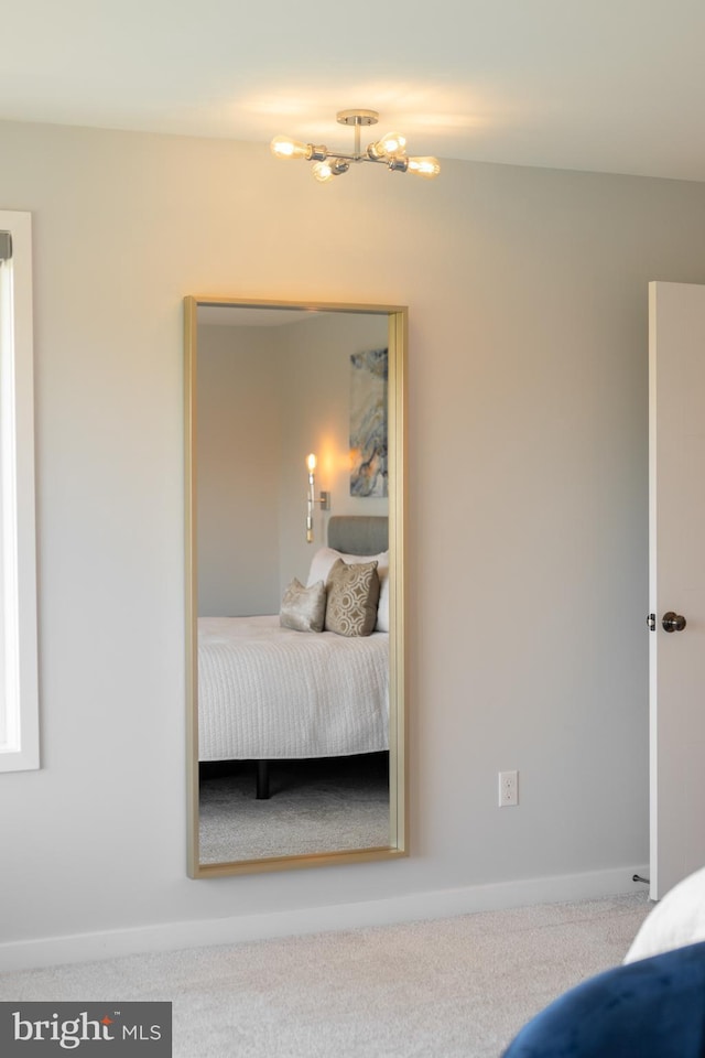 bedroom with baseboards, a chandelier, and carpet