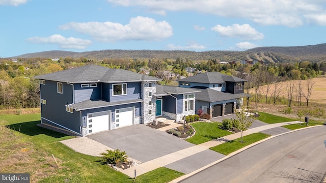 view of front facade with a front yard, a mountain view, aphalt driveway, an attached garage, and stone siding