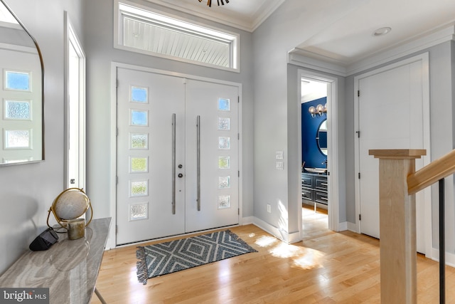 entryway featuring ornamental molding, a healthy amount of sunlight, and light wood-type flooring