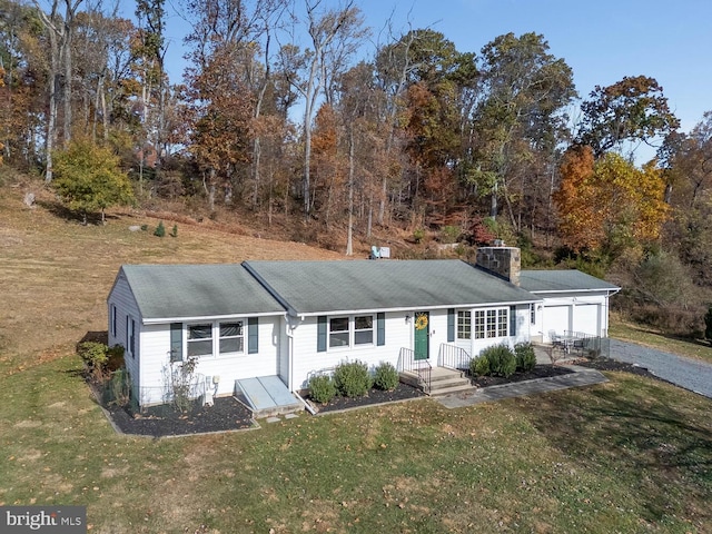 single story home featuring a chimney, a front lawn, and gravel driveway