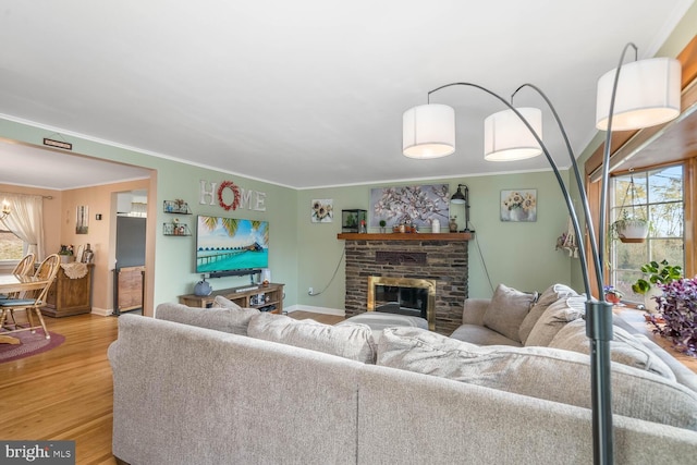 living room with crown molding, a fireplace, a wealth of natural light, and light wood-style floors