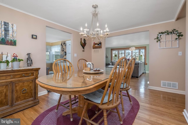 dining area featuring a chandelier, baseboards, visible vents, and light wood-style floors