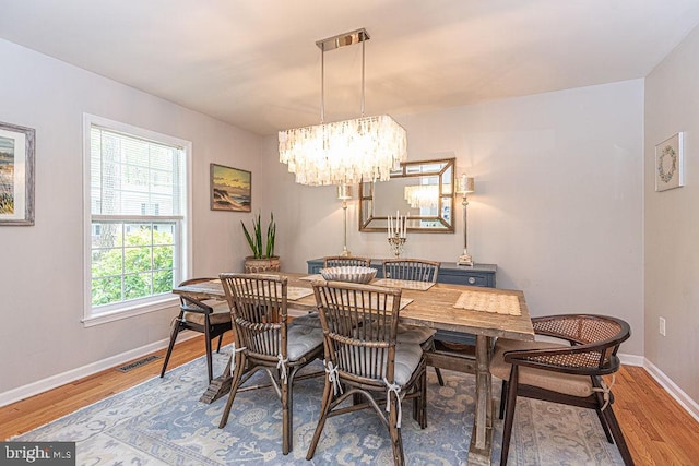 dining area featuring light wood-style floors, baseboards, an inviting chandelier, and visible vents