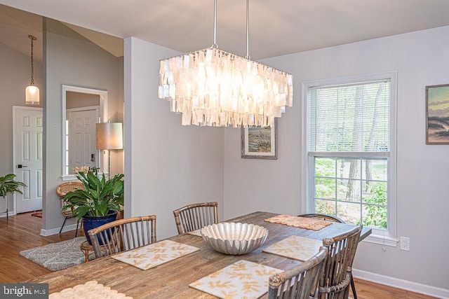 dining space with baseboards, wood finished floors, and a notable chandelier