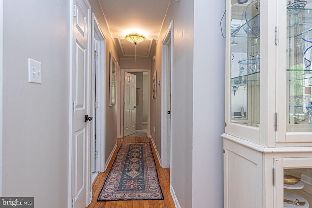 hall with baseboards, attic access, and light wood finished floors