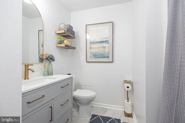 full bath featuring vanity, marble finish floor, baseboards, and toilet
