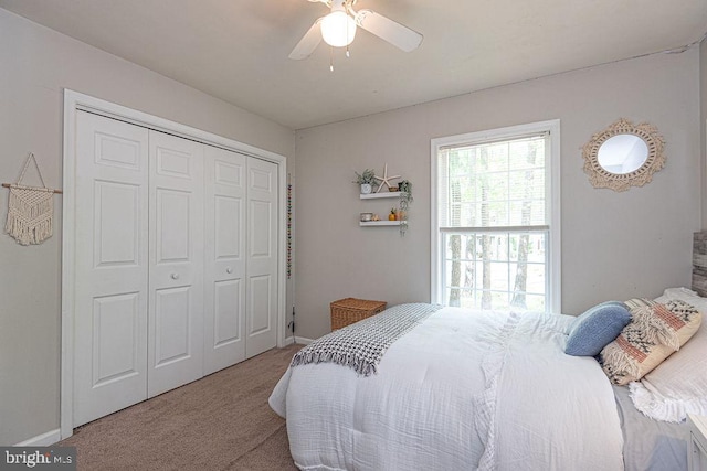 carpeted bedroom with a closet, baseboards, and ceiling fan