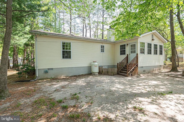 back of house with crawl space, a chimney, and entry steps