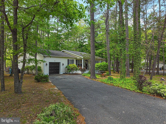 single story home with an attached garage, roof with shingles, and aphalt driveway
