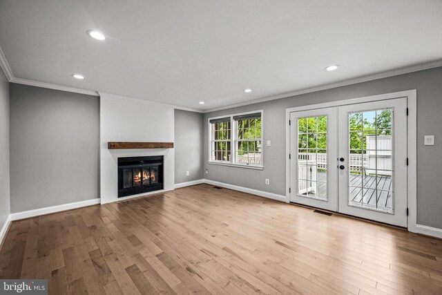 unfurnished living room featuring ornamental molding, wood finished floors, recessed lighting, french doors, and a glass covered fireplace