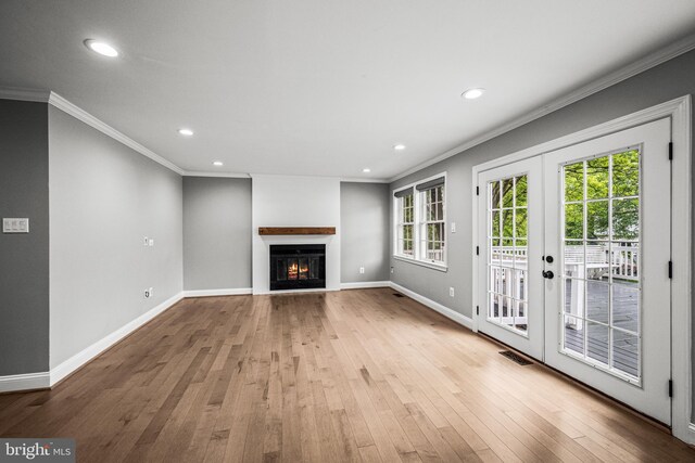 unfurnished living room featuring wood-type flooring, a glass covered fireplace, recessed lighting, crown molding, and french doors