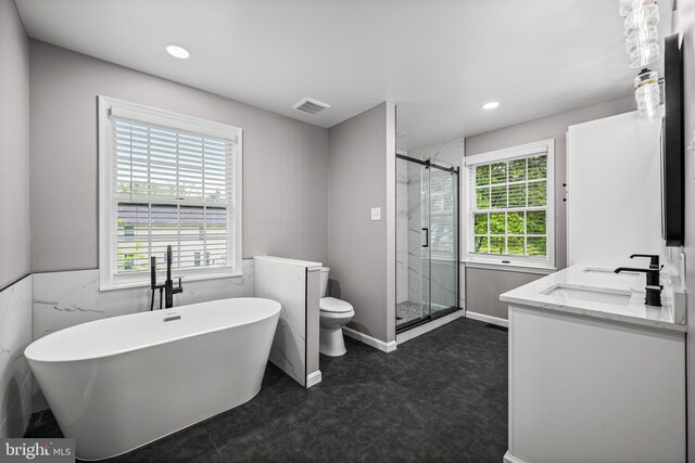 bathroom with a shower stall, toilet, a freestanding tub, recessed lighting, and double vanity