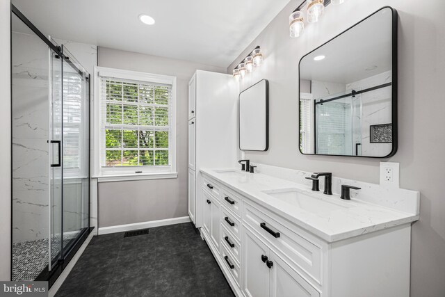 bathroom with a marble finish shower, baseboards, double vanity, and recessed lighting