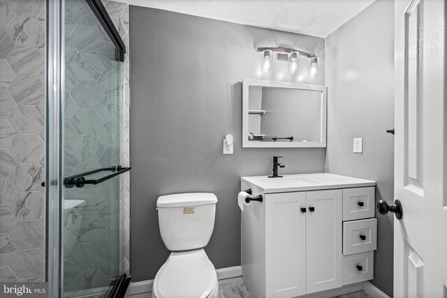 bathroom with a stall shower, toilet, vanity, baseboards, and marble look tiles