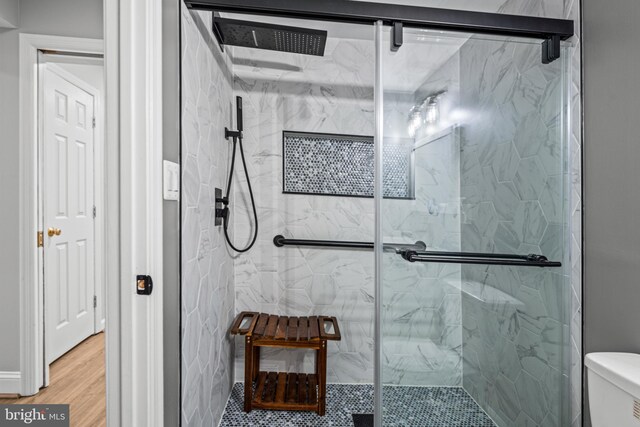 full bath featuring a marble finish shower, toilet, and wood finished floors