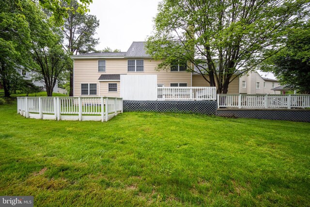 back of property featuring a wooden deck and a lawn