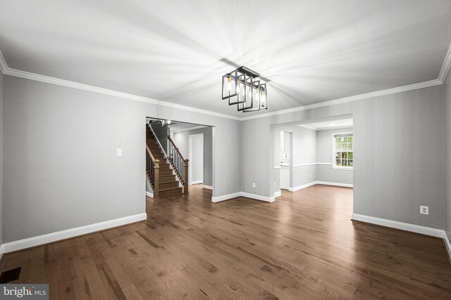 unfurnished room with stairway, baseboards, wood finished floors, and ornamental molding