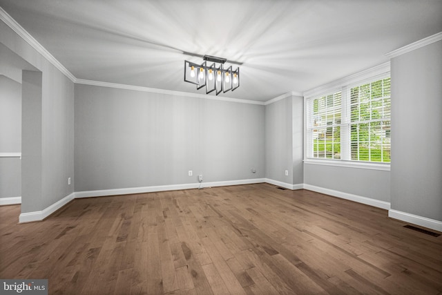 unfurnished room featuring wood finished floors, a chandelier, ornamental molding, and baseboards