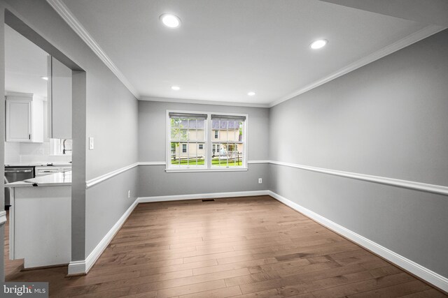 empty room with recessed lighting, wood finished floors, baseboards, and ornamental molding
