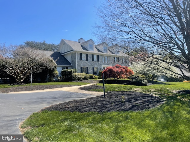 view of side of home with a lawn, a chimney, and stone siding