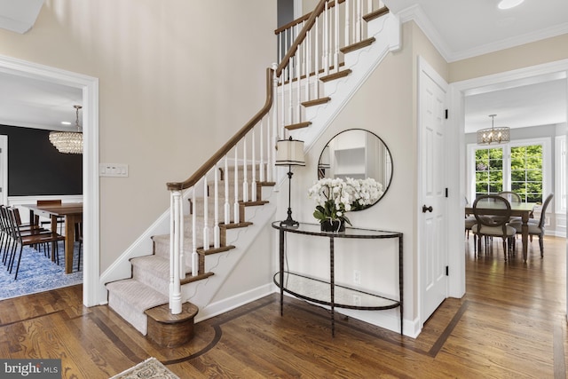 stairs featuring baseboards, ornamental molding, wood finished floors, and a chandelier