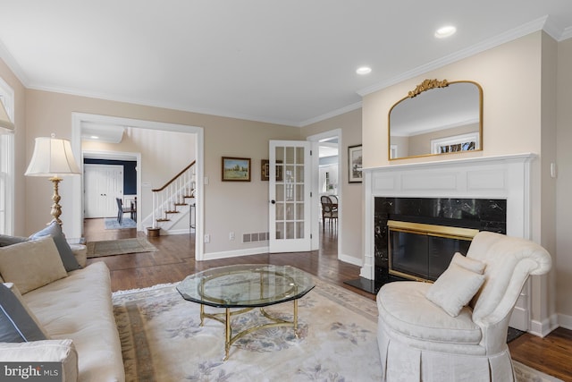 living room featuring a high end fireplace, baseboards, and wood finished floors