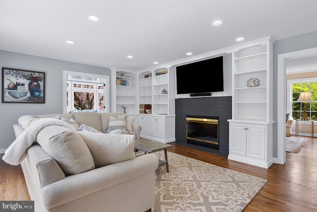 living room featuring recessed lighting, baseboards, a brick fireplace, and wood finished floors
