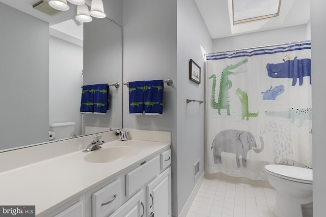 full bath featuring tile patterned flooring, a skylight, toilet, and vanity