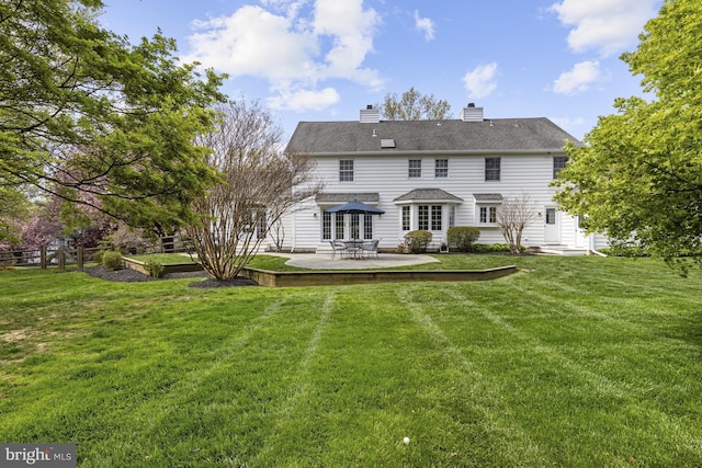 back of property with fence, entry steps, a chimney, a patio area, and a lawn