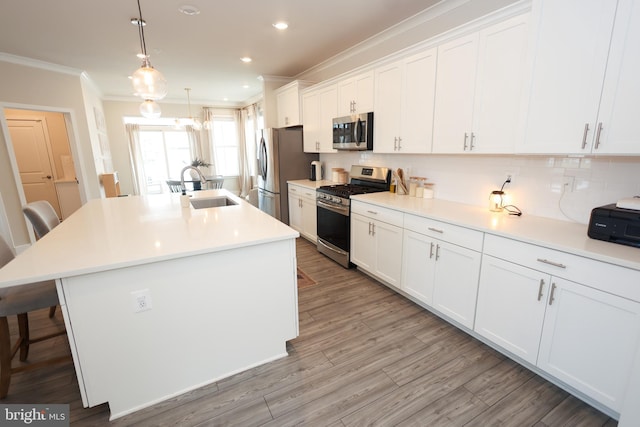 kitchen with stainless steel appliances, a sink, ornamental molding, a kitchen bar, and white cabinets