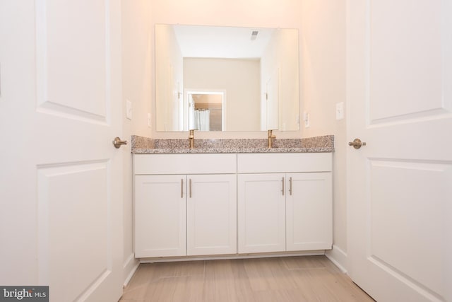 bathroom with double vanity and baseboards