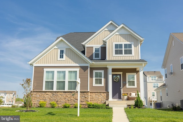 craftsman-style home with board and batten siding, stone siding, a front yard, and central AC