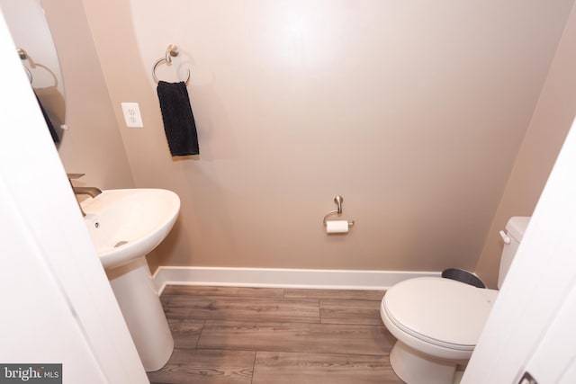 bathroom with wood finished floors, toilet, and baseboards