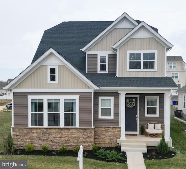 craftsman inspired home featuring stone siding, a shingled roof, and board and batten siding