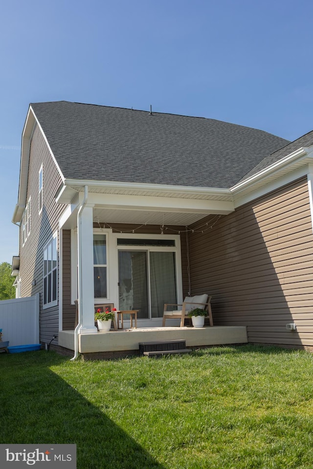 back of house featuring a lawn and a shingled roof
