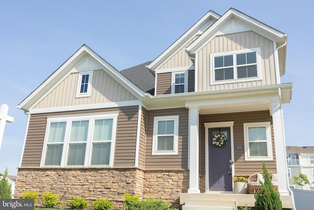 craftsman inspired home featuring board and batten siding, stone siding, and roof with shingles