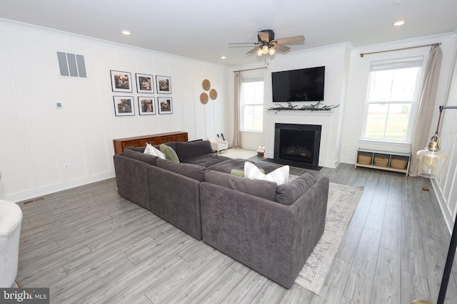 living area with ornamental molding, ceiling fan, wood finished floors, a fireplace with flush hearth, and recessed lighting