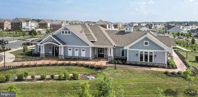 view of front of house with a residential view, board and batten siding, stone siding, and a front lawn