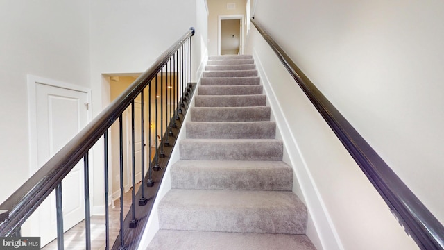 staircase with carpet floors and a towering ceiling