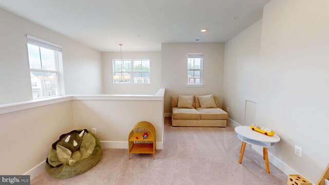 living area with baseboards and light carpet
