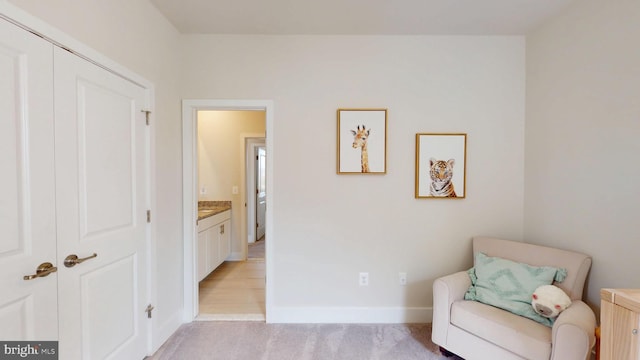 living area featuring light carpet and baseboards