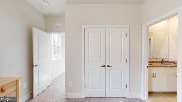 unfurnished bedroom featuring a closet, baseboards, bar with sink, and ensuite bathroom