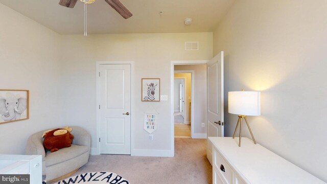living area featuring light colored carpet, ceiling fan, and baseboards