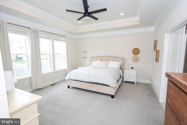 bedroom featuring crown molding, light colored carpet, baseboards, ceiling fan, and a tray ceiling